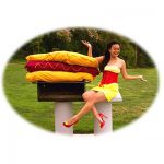 Competitive eater, Mary Bowers models her larger than life appetite with a hotdog big enough for the whole party